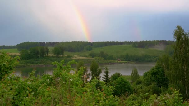 Doble arco iris en un cielo gris después de la lluvia sobre el lago del bosque — Vídeo de stock