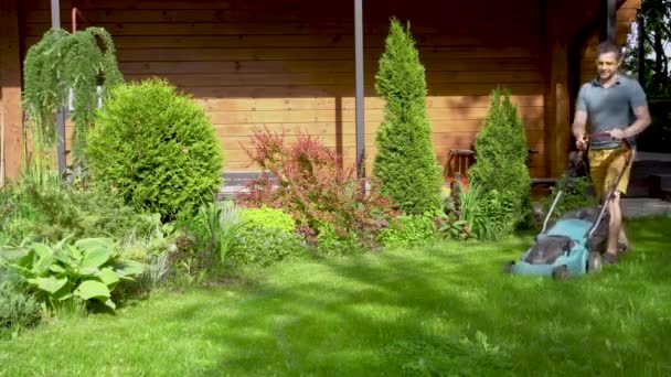 Çalışkan sahibi güneşli bir yaz gününde çimlerle ilgilenir.. — Stok video