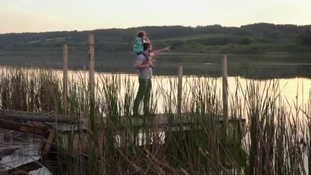 Pappa och dotter beundrar solnedgången över sjön. Tillbringa tid tillsammans — Stockvideo