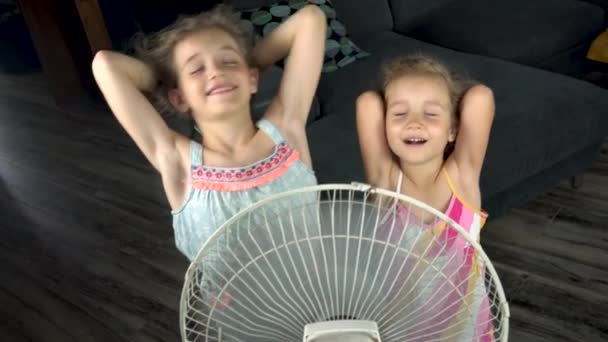 As meninas estão se salvando do calor sob o ventilador. — Vídeo de Stock
