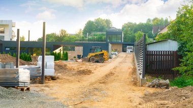 Özel bir evin inşaatı. Fren dümeni yükleyicisi inşaat alanında çalışıyor. Manzara tasarımında zemini düzleştiriyorum. Sitenin dikey düzeni. Bir giriş grubu ve yürüyüş yolu inşaatı.