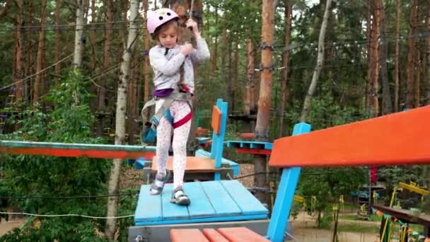 Девушку тестируют на канатной дороге в парке со специальным альпинистским снаряжением. — стоковое видео