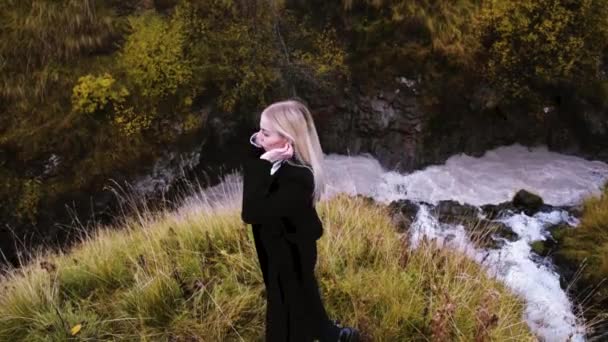Krásná, stylová blondýnka pózující na pozadí podzimní přírody a horské řeky. Video v HD kvalitě — Stock video