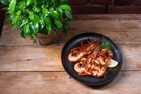 Delicious fried langoustines in sauce on a black plate, prepared in an Asian style. Fast and ready meal concept — Stock Photo, Image