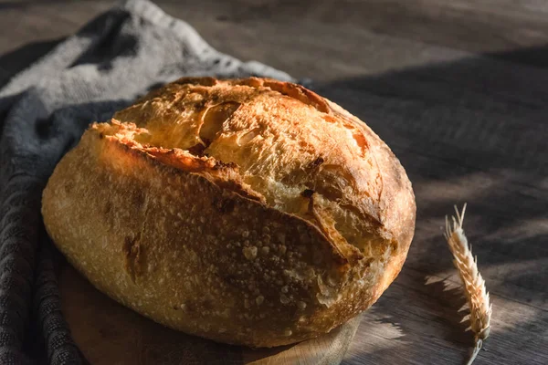 El pan de tarta hecho a mano se encuentra en una superficie de madera junto a las espigas de trigo. Agricultura y hogar concepto de cocción —  Fotos de Stock