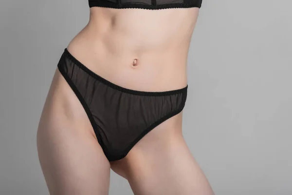 Gri arka planda bikinili güzel, narin bir kadın figürü. Moda fotoğrafçılığı ve giysi konsepti