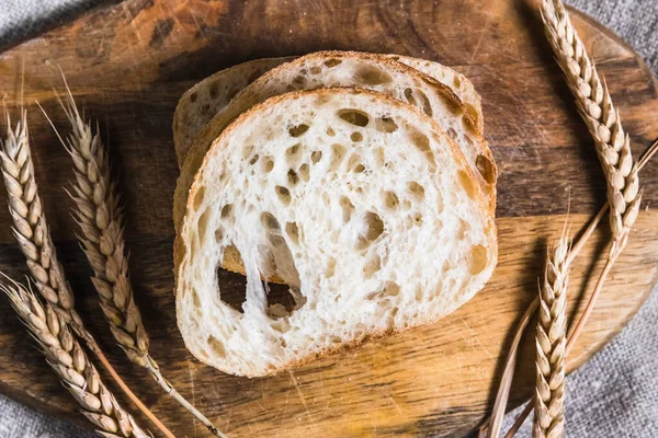 Una hogaza de ciabatta tradicional en una bandeja de madera sobre la mesa. Concepto de pan artesanal —  Fotos de Stock