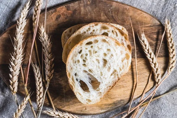 Una hogaza de ciabatta tradicional en una bandeja de madera sobre la mesa. Concepto de pan artesanal —  Fotos de Stock