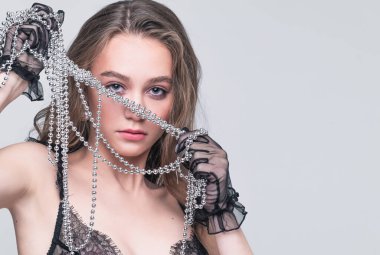 Makyajlı ve elinde boncuklarla güzel bir kadın. Moda çekimi ve modaya uygun kıyafetler.