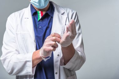 Ellerine eldiven takan tıbbi giysiler giymiş bir doktorun yakın çekimi. Sağlık ve koruma kavramı