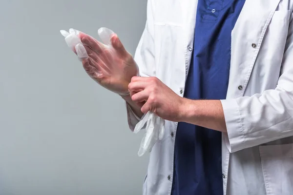 Крупный план доктора в медицинской одежде, который надевает перчатки на руки. Концепция здоровья и защиты — стоковое фото