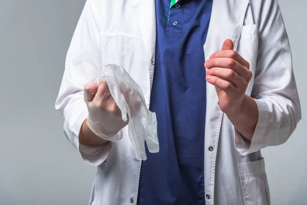 Крупный план доктора в медицинской одежде, который надевает перчатки на руки. Концепция здоровья и защиты — стоковое фото