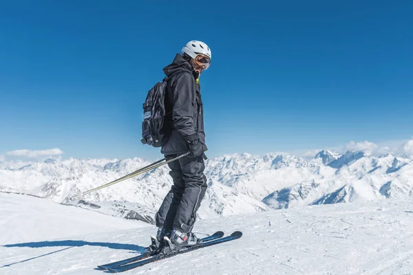 Un uomo con gli sci si erge in cima alle montagne godendo il paesaggio. Sci alpino, estremo relax — Foto Stock