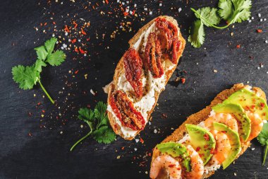 Karanlık bir yüzeyde karides, peynir, avokado ve domatesli sandviç. Sağlıklı yemek ve sağlıklı yaşam tarzı kavramı.