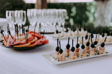 Lokanta masası, zeytinli peynir, doğranmış karpuz portakallı tabak, meyve servisi, bulanık arka plan ve bardaklar. 