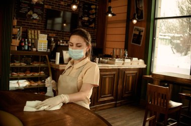 Kafe çalışanı Coronavirüs 'ten maske takarak bakteri virüslerini dezenfekte ediyor.