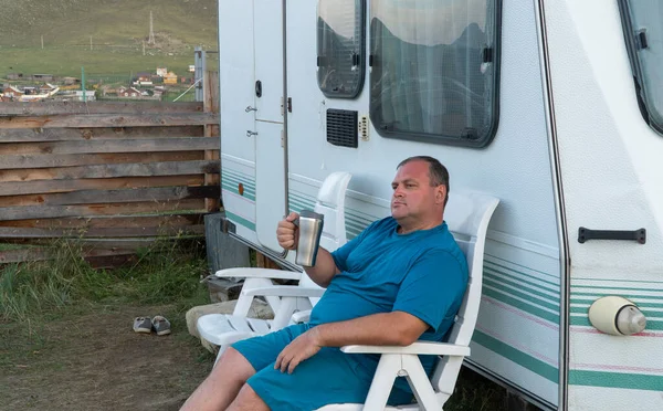 Mann entspannt sich mit Wohnmobil. Person im Urlaub mit einem Becher in der Hand. das Konzept der Freizeitaktivitäten — Stockfoto