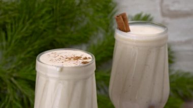 İçkiyi uzun kokteyl bardaklarına dök. Üzerine hindistan cevizi serp. Hindistan cevizi ve tarçınlı eggnog Noel kokteyli. Geleneksel bayram içkisi. Dönen kupa. seçici odak. 