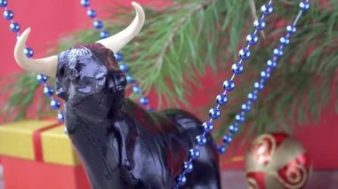 Noel boğası. 2021 yılının sembolü olarak boğa. Kırmızı arka planda şenlikli Noel süsleri. Doğu takvimindeki boğa yılı. xmas boncukları