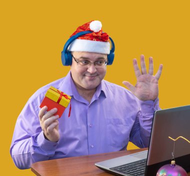 Noel Baba takan bir adam arkadaşlarıyla video görüşmesinde konuşuyor. Gözlüklü yetişkin yeteneğini gösteriyor. Tatilin internet üzerinden kutlanması. Noel görüntülü sohbeti. İnternette tatil tebrik ederim..