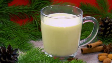 Geleneksel bayram içkisi. Çiğ tavuk yumurtası ve süte dayalı tatlı bir içecek. Rendelenmiş hindistan cevizi ve tarçınlı Noel kokteyli. Külahlı bir ladin dalının arka planı. xmas iç..