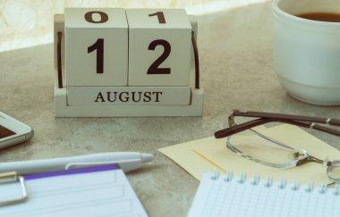 12 Ağustos, takvimdeki tarih. Uluslararası Lefthanders Günü. Ay ve gün içinde el yapımı ahşap küp. Gün için planlama.