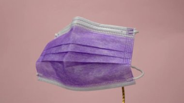 Göz kamaştırıcı mor cerrahi koruyucu maske. Pembe arka planda tıbbi solunum bandajı var. Corona virüsüne karşı korunmak için çok renkli antiviral maske. Karantina, evde kal.