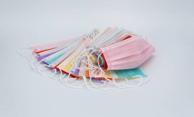 Beyaz arka planda renkli tıbbi maskeler. Virüs ve enfeksiyonlardan korunmak için yüzünde steril bandaj var. Koronavirüse karşı korunmak için antiviral tıbbi maske. COVID-19 salgını.