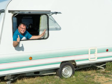 Turist karavanındaki mutlu adam. Büyük karavan karavanı, yolcuların rahat etmesini sağlar. Eğlence aracı karavanı. Yaz tatilleri ve turizm. Boşluğu kopyala.