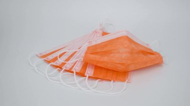 Beyaz arka planda turuncu renkli tek kullanımlık maske. Korona virüsüne karşı korunmak için antiviral tıbbi maske. Göz kamaştırıcı cerrahi koruyucu maske. Kilitlenme. ulusal maske görevi