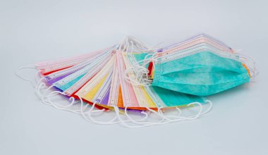 Beyaz arka planda renkli tıbbi maskeler. Virüs ve enfeksiyonlardan korunmak için yüzünde steril bandaj var.