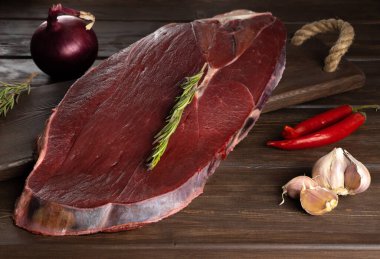 Tahta zemin üzerinde biberiye filizi olan bir parça taze et. Et yemekleri pişiriyorum.