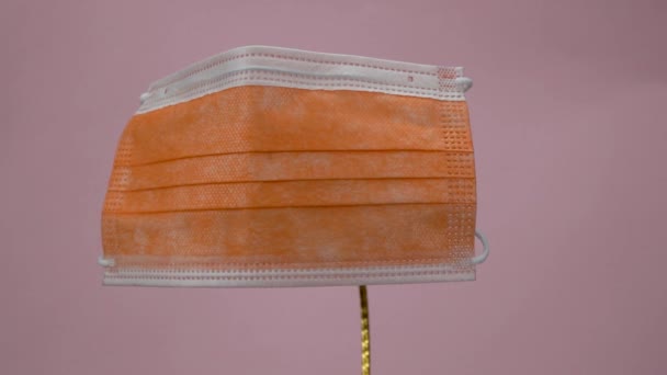 Einmalmaske Orange Auf Rosa Hintergrund Antivirale Medizinische Maske Zum Schutz — Stockvideo