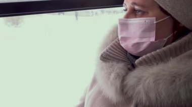 Tıbbi maskeli bir kadın otobüse biniyor. Zorunlu maske takmak. Maskeleme gereksinimleri. Kilitlenme. Ulusal maske zorunluluğu. Maske yarışması. Cerrahi koruyucu maske. Tıbbi solunum bandajı yüzü.