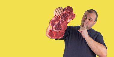 fat man holds a raw piece of meat in his hand. person cannot eat meat he is on a diet or a vegetarian. celebrating International Day Without Meat and World Vegetarian Day. support for vegetarianism. clipart
