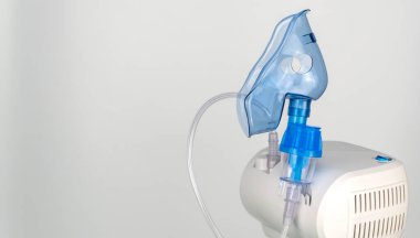 Beyaz bir arka planda nebulizör ve nefes maskesi. Solunum hastalıklarının ve alerjilerin tedavisi
