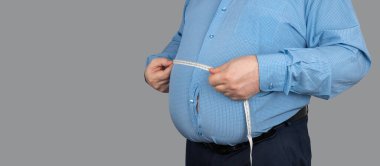 Şişman adam karnının ölçüsünü bir santimetre şeritle ölçüyor. Gömlek büyük yağ birikintileri yüzünden yırtılmış. İş adamı obez ve diyete devam etmeye karar verdi. Kilo Verme Günü.