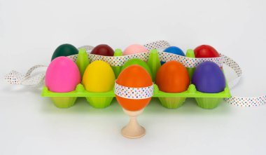 Tahta bir stantta paskalya yumurtası. Renkli yumurtalar kutuda. Plastik paket. Bir şenlik kurdelesiyle süslenmiş..