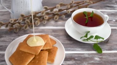 delicious cookies with condensed milk and black tea with mint. selective focus. light breakfast is served on a wooden table. porcelain cup with tonic mint tea. decorated with pussy willow. 