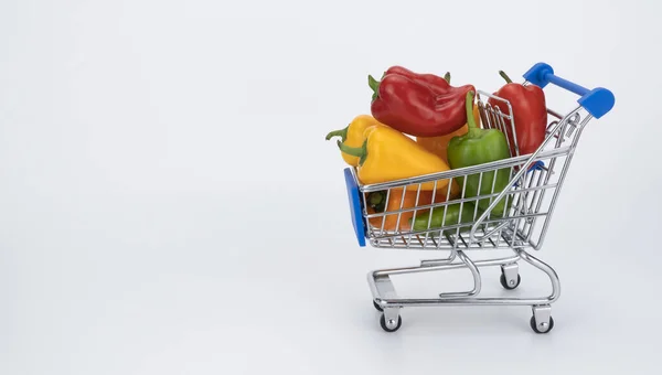 Carrinho de supermercado em miniatura cheio de pimentas coloridas. cesta de supermercado com páprica. — Fotografia de Stock