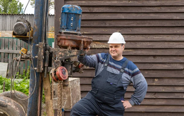 Mann steht in der Nähe einer Bohrinsel. Brunnen für Trinkwasser bohren. Stockbild