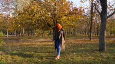 Sonbahar parkında kızıl saçlı kız.