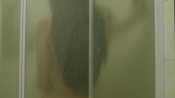 Ein Kerl mit einem nackten Mädchen hinter dem Glas in der Dusche — Stockvideo