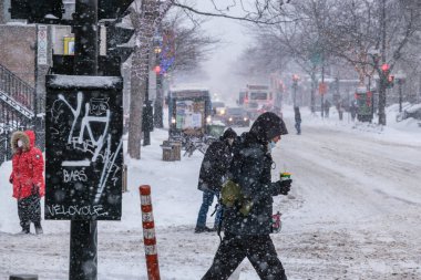 Montreal, CA - 2 Şubat 2021: Şiddetli kar yağışı sırasında koruyucu maskeli insanlar sokakta yürüyor