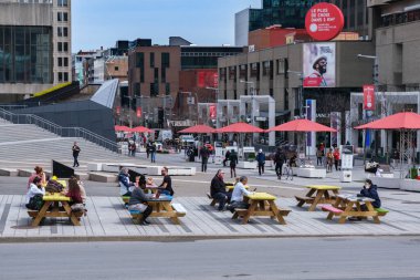 Montreal, CA - 28 Nisan 2021: Montreal şehir merkezindeki St. Catherine Caddesi 'nde piknik masalarında oturan insanlar.
