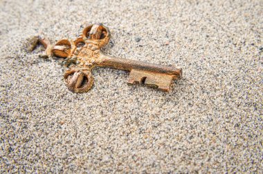 Old key in the sand clipart