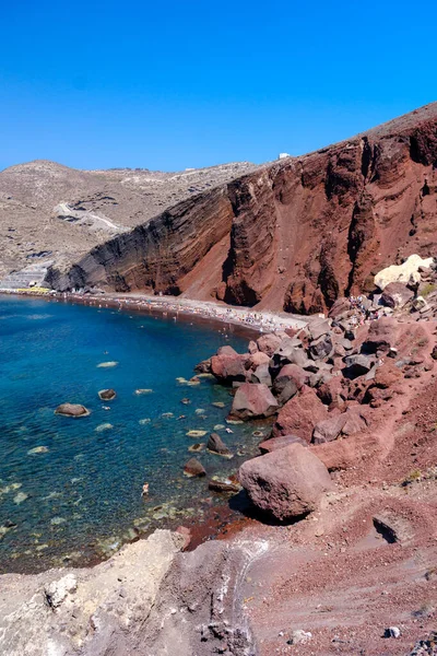 Santorini, GR - 4 Eylül 2025: Santorini 'deki ünlü Kızıl Kumsal, açık mavi Ege Denizi' nin yanındaki parlak kırmızı volkanik kaya ve kumu gösteriyor