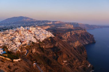 Santorini, GR - 4 Eylül 2025: Günbatımında ikonik beyaz boyanmış binaları, dramatik uçurumları ve Ege Denizi ile Fira şehir manzarasını görüntüler