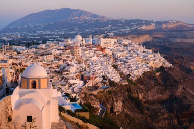 Santorini, GR - 4 Eylül 2025: Günbatımında ikonik beyaz boyanmış binaları, dramatik uçurumları ve Ege Denizi ile Fira şehir manzarasını görüntüler