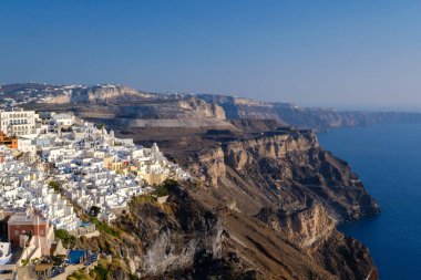 Santorini, GR - 4 Eylül 2025: Fira 'da turistler, açık Santorini gökyüzünün altındaki engin kaldera ve Ege Denizi' ne bakarak ünlü bir bakış açısıyla görülüyor